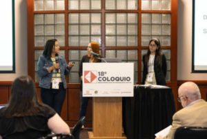 Three people talking in front of audience